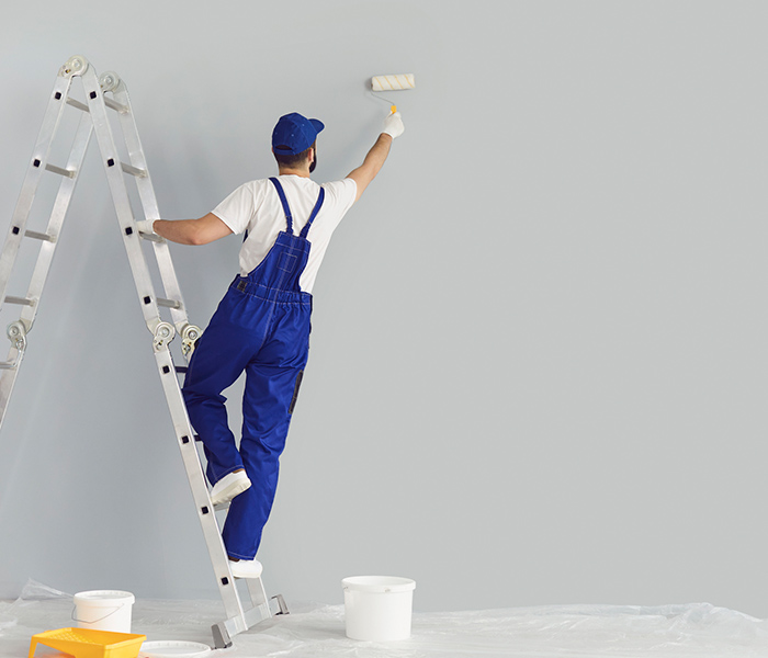 contractor painting grey wall with roller brush