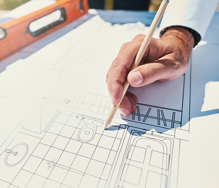 man holding pencil and pointing it at picture of bathroom on house drawings